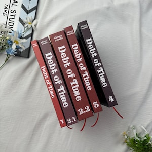 May include: A collection of five books titled "Debt of Time" with varying shades of red and burgundy covers. Each book has a red ribbon bookmark. The numbers 1, 2.1, 2.2, 3, and 4 are visible on the spines.