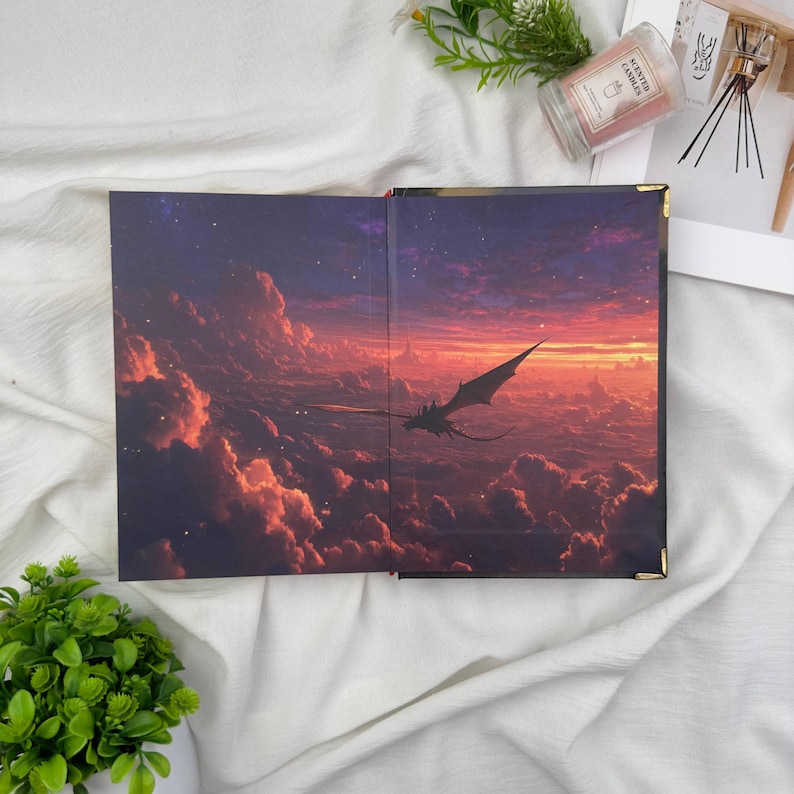 May include: Open book with a fantasy landscape illustration. The artwork depicts a dragon soaring through a sunset sky filled with clouds. The book's interior features a detailed, colorful painting with a dramatic, epic theme.