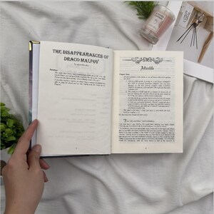 Puede incluir: Un libro abierto titulado "The Disappearances of Draco Malfoy" con texto en las p&aacute;ginas. El libro tiene un borde dorado y est&aacute; abierto para revelar texto impreso. La p&aacute;gina de la derecha se titula "Afterlife".