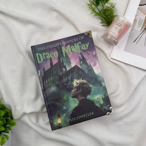 Puede incluir: Un libro de tapa dura titulado "The Disappearances of Draco Malfoy" con una ilustraci&oacute;n de fantas&iacute;a de un castillo y un joven. El libro tiene protectores de esquina dorados y la palabra "SPEECHWRITER" en la parte inferior. Una vela y una revista est&aacute;n en el fondo.