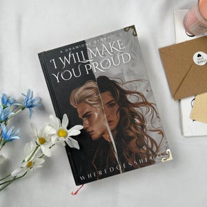 May include: A book titled "I Will Make You Proud" with a cover featuring two illustrated faces. The book has a black spine and the text "WHERE DOES SHE GO" at the bottom. A sprig of white and blue flowers is next to the book.