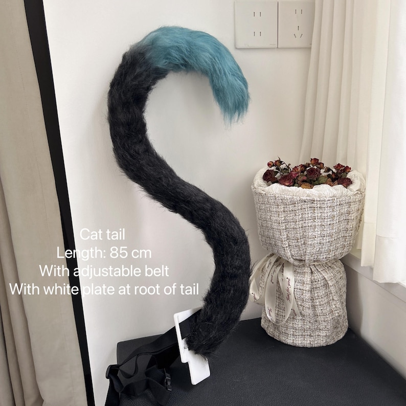May include: A black and blue cat tail costume with an adjustable belt and a white plate at the base of the tail. The tail is 85 cm long.