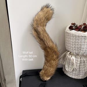 May include: A brown and black wolf tail costume accessory with a belt. The tail is 50 cm long. Wolf tail. Length: 50 cm. With belt.