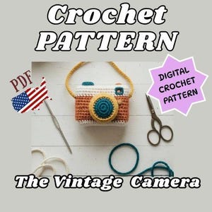 Op de afbeelding: Een haakpatroon voor een vintage camera. De camera is bruin, wit en blauwgroen met een gele band en lens. De afbeelding bevat een haaknaald, een schaar en de tekst "Crochet Pattern", "PDF", "Digital Crochet Pattern" en "The Vintage Camera".