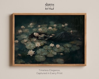 May include: A framed art print featuring a person with long dark hair floating in dark water among white water lilies and green lily pads. The print is enclosed in a light wood frame. Text at the top reads NORTH STUDIO ART PRINT.