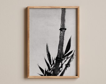 Puede incluir: Una lámina de arte mural enmarcada que presenta una pintura a tinta negra de tallos y hojas de bambú sobre un fondo gris claro. La obra está contenida en un marco de madera de tono claro, con un perfil rectangular y un acabado liso.