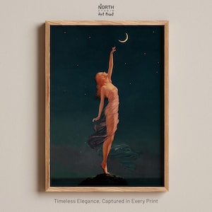 Pode incluir: Uma impressão artística emoldurada intitulada North Studio Art Print apresentando uma figura com uma vestimenta rosa fluida alcançando uma lua crescente em um céu noturno estrelado. A figura está sobre uma rocha escura. O texto na parte inferior diz Timeless Elegance, Captured in Every Print.
