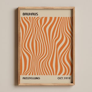 Könnte beinhalten: Ein rechteckiges gerahmtes Poster mit beigem Hintergrund und einem zentralen Muster aus vertikalen, wellenförmigen orangefarbenen Linien. Der Text BAUHAUS steht oben in Schwarz, während AUSSTELLUNG und OCT. 1919 unten in Schwarz stehen.