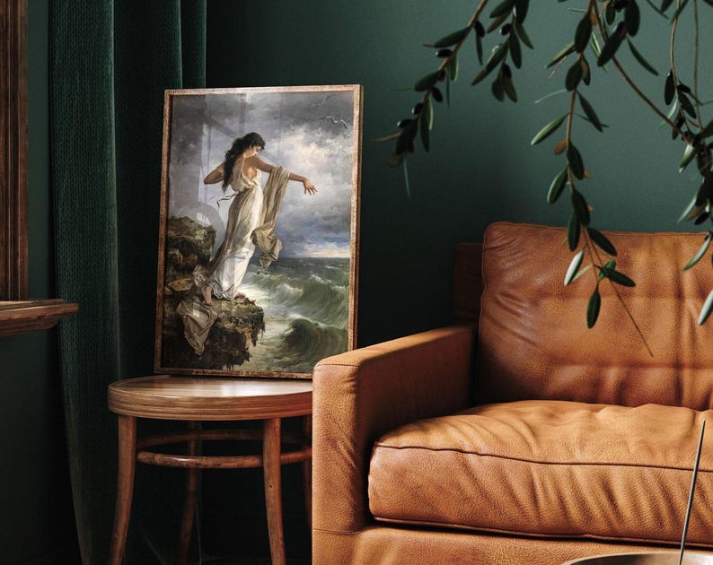 a painting of a woman standing on a cliff, with a stormy sea in the background. The painting is displayed on a wooden table, and there is a brown leather couch in the background.