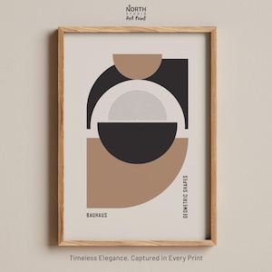 Op de afbeelding: Ingelijste kunstdruk met een geometrisch ontwerp in zwart, beige en bruin. De print bevat het woord "BAUHAUS" en de tekst "GEOMETRIC SHAPES". De lijst is van lichtgekleurd hout.
