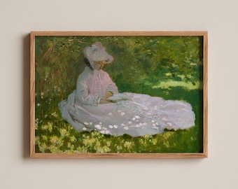 May include: A framed impressionist painting depicting a figure in a light pink dress and matching bonnet sitting on a grassy field filled with yellow flowers. The figure is reading a book under the shade of green trees with dappled sunlight.