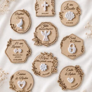 Peut inclure: Neuf plaques en bois gravées au laser avec des bordures florales et du texte, chacune ornée d'un emblème en argile blanche incluant une croix, un coquillage, une colombe, un ange, un nœud, un cadenas, une fleur et des cœurs avec des dates.