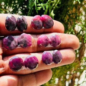 Może przedstawiać: Sześć par owalnych, fasetowanych, fioletowych kamieni szlachetnych. Kamienie szlachetne są ułożone w trzech rzędach po dwa, przy czym każda para znajduje się na małym białym podkładzie.