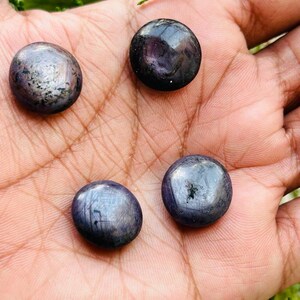 May include: Four round, dark blue gemstones with a metallic sheen. The gemstones are smooth and polished.