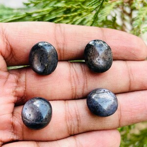 May include: Four round, dark blue gemstones with a metallic sheen. The stones are smooth and polished.