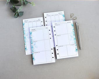 May include: Three white planner refill pages with a blue watercolor floral border, featuring black text for days of the week and dates. The pages have punched holes on the left side for a binder. A silver metal pen and two paper clips are included.