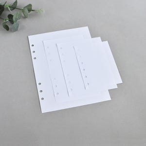 May include: A stack of four white rectangular paper sheets of varying sizes, each featuring a vertical row of circular punched holes along the left edge, designed for insertion into a binder or planner system for organized note-taking.