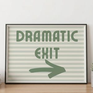 May include: A rectangular framed wall art print featuring horizontal light green and white stripes. The text DRAMATIC EXIT is printed in a bold, dark green sans-serif font, positioned above a dark green hand-drawn arrow pointing to the right.