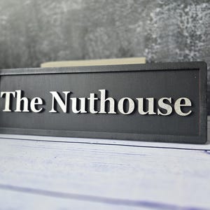 The Nuthouse / Divertido letrero de madera con letras 3D en relieve / Decoración de pared en negro y plateado / Un regalo original para el hogar familiar