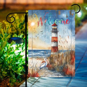 May include: A welcome garden flag with a lighthouse, a pelican, and the word "Welcome" in colorful letters. The flag has a blue, white, and brown background with a watercolor effect.