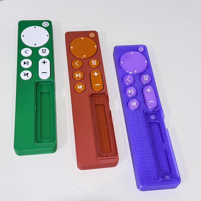 May include: Three colorful remote controls in green, red, and purple. Each has a circular power button, directional controls, and volume buttons. The remotes are rectangular with a slot on the bottom.