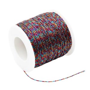 Puede incluir: Una bobina de hilo multicolor con un núcleo blanco. El hilo es una mezcla de rojo, azul, verde y morado, creando un efecto brillante. La bobina está sobre un fondo blanco.
