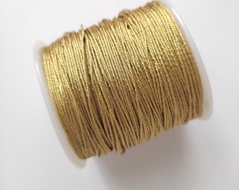 Puede incluir: Un carrete de cordón metálico dorado, enrollado apretadamente y listo para proyectos de manualidades.