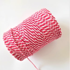 May include: A roll of red and white baker's twine. The twine is striped with alternating red and white stripes.