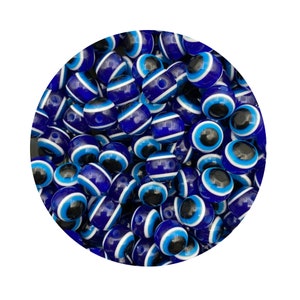 May include: A close-up of a collection of blue and white evil eye beads. The beads are round and have a white circle in the center with a blue eye.