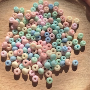 K&ouml;nnte beinhalten: Eine Schale mit pastellfarbenen Glasperlen. Die Perlen sind in den Farben Rosa, Blau, Gr&uuml;n und Wei&szlig;.