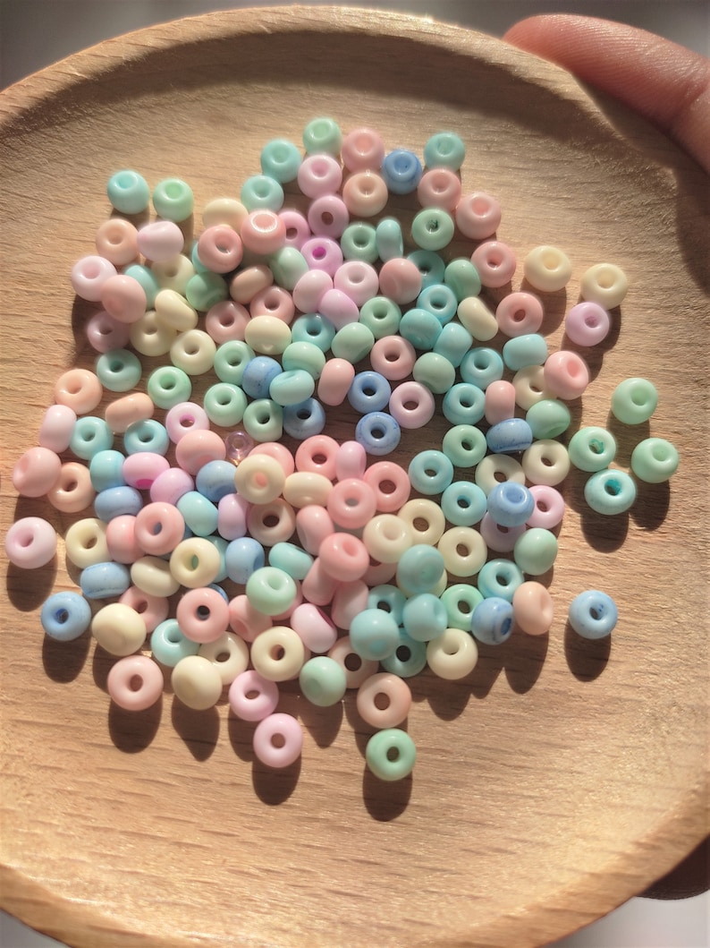 K&ouml;nnte beinhalten: Eine Schale mit pastellfarbenen Glasperlen. Die Perlen sind in den Farben Rosa, Blau, Gr&uuml;n und Wei&szlig;.