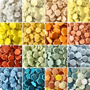 Puede incluir: Una colección de azulejos de mosaico hexagonales en varios colores, incluyendo blanco, amarillo, naranja, rojo, verde, azul y melocotón. Los azulejos están dispuestos en un patrón de cuadrícula, mostrando la diversa paleta de colores y texturas.