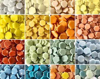 Può includere: Una collezione di tessere di mosaico esagonali in vari colori, tra cui bianco, giallo, arancione, rosso, verde, blu e pesca. Le tessere sono disposte in una griglia, mostrando la diversa tavolozza di colori e le texture.