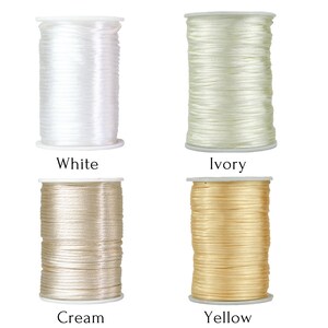 Puede incluir: Cuatro carretes de hilo en diferentes colores: blanco, marfil, crema y amarillo. Los carretes son todos del mismo tama&ntilde;o y forma, y est&aacute;n dispuestos en una cuadr&iacute;cula.