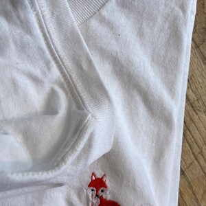 Puede incluir: Camiseta blanca con un zorro bordado en rojo y el texto "For Fox Sake" en negro.