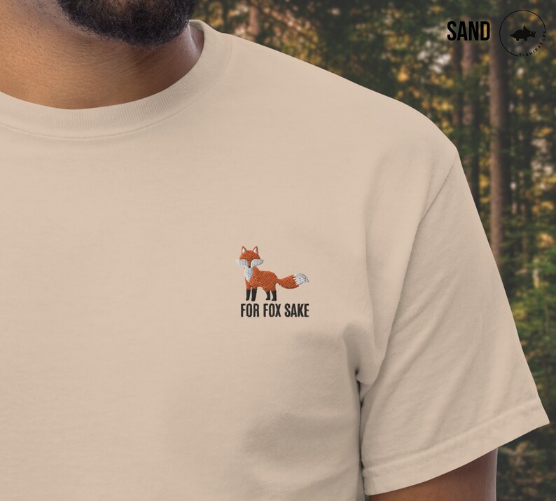 Puede incluir: Una camiseta beige con un zorro bordado y el texto "FOR FOX SAKE".