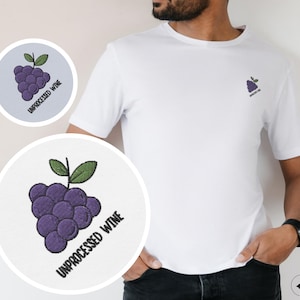 Puede incluir: Camiseta blanca con un diseño de uva morada y el texto "UNPROCESSED WINE" bordado en la parte delantera.