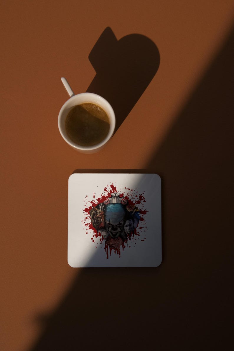 May include: White ceramic coaster with a red, white, and blue graphic of a clown's face surrounded by blood splatters.