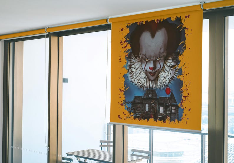 May include: A yellow window blind with a graphic of a scary clown with a red balloon and a house in the background.