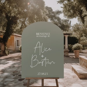 May include: A green welcome sign with a rounded arch top. The sign reads "Bienvenue au mariage de Alice + Bastien 27.08.23".