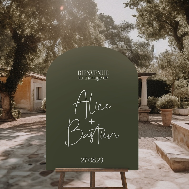 May include: A green welcome sign with a rounded arch top. The sign reads "Bienvenue au mariage de Alice + Bastien 27.08.23".