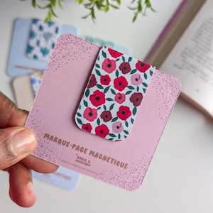 Peut inclure: Signet magnétique rose avec un motif floral de coquelicots rouges sur fond blanc. Le signet porte l'inscription "Marque-Page Magnétique + Avril & Novembre www.avrilnovembre.com".