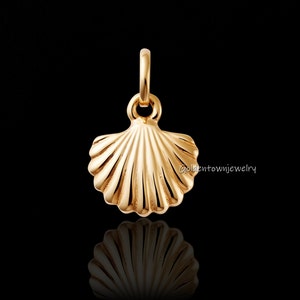 May include: A gold-colored seashell pendant with a loop for a necklace. The pendant has a detailed, ridged design and is set against a black background. The text "Goldentownjewelry" is visible on the right side.