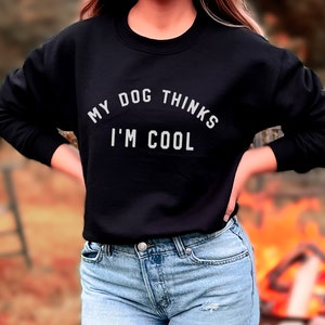 May include: A black sweatshirt with the text "My dog thinks I'm cool" in white lettering.