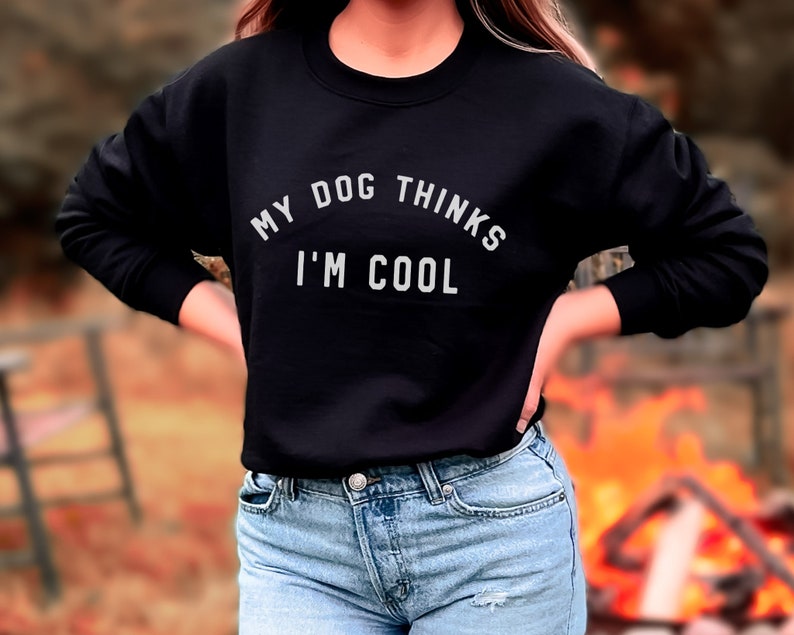May include: A black sweatshirt with the text "My dog thinks I'm cool" in white lettering.