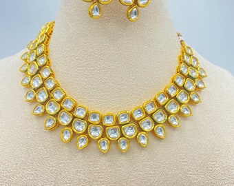 Peut inclure: Un collier et des boucles d'oreilles en or sertis de pierres claires et facettées. Le collier est de style ras de cou avec plusieurs rangées de pierres. Les boucles d'oreilles sont de style pendantes avec plusieurs pierres.