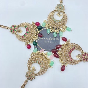 May include: An ornate, gold-toned headpiece with intricate floral and crescent moon designs. The jewelry features colorful gemstones in shades of red, green, and pink, along with small white pearls. The brand name "purnisha jewels" is visible.