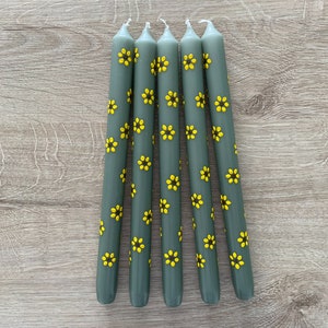 Handbeschilderde kaarsen. Bloemen geschilderde kaarsen. Groene dinerkaarsen met gele zonnebloemen. Gele zonnebloemen met een donkerbruine kern.