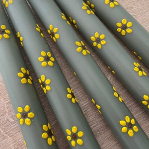 Handbeschilderde kaarsen. Bloemen geschilderde kaarsen. Groene dinerkaarsen met gele zonnebloemen. Gele zonnebloemen met een donkerbruine kern.