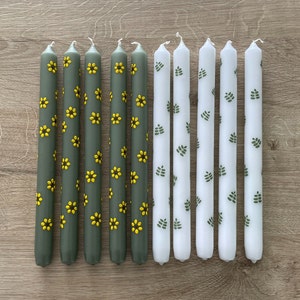 Bloemen geschilderde kaarsen. Dinerkaarsen. Handbeschilderde kaarsen. Groene kaarsen met gele zonnebloemen en witte kaarsen met groene blaadjes.